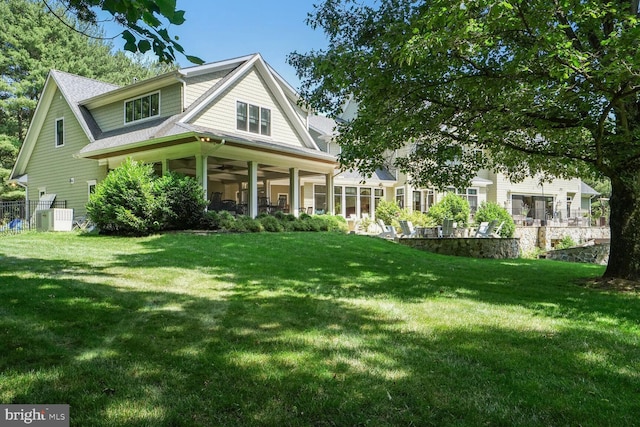 rear view of property featuring a lawn and central AC unit