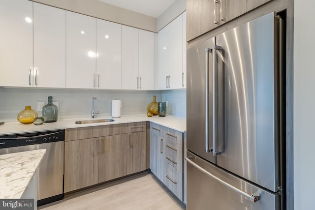 kitchen featuring light countertops, backsplash, appliances with stainless steel finishes, and a sink