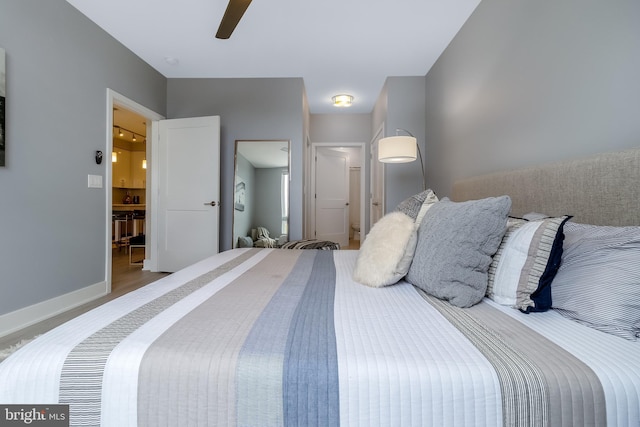 bedroom with a ceiling fan, ensuite bath, wood finished floors, and baseboards