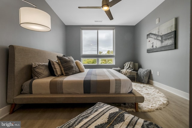 bedroom featuring visible vents, ceiling fan, baseboards, and wood finished floors