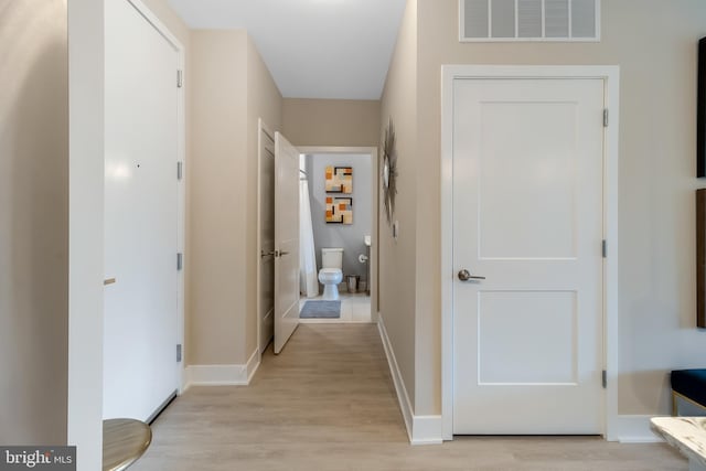 corridor featuring visible vents, baseboards, and light wood-style floors