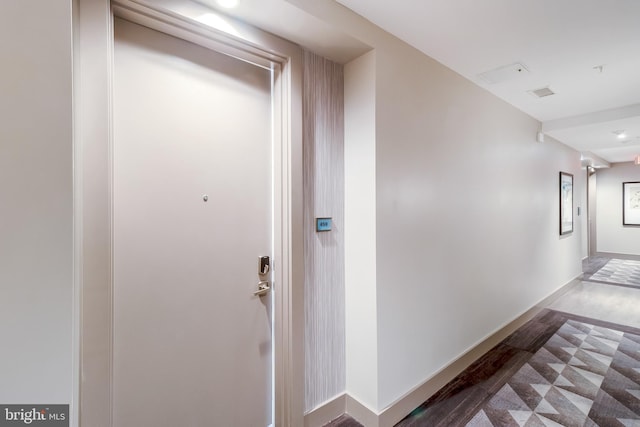 hall featuring visible vents, baseboards, and wood finished floors