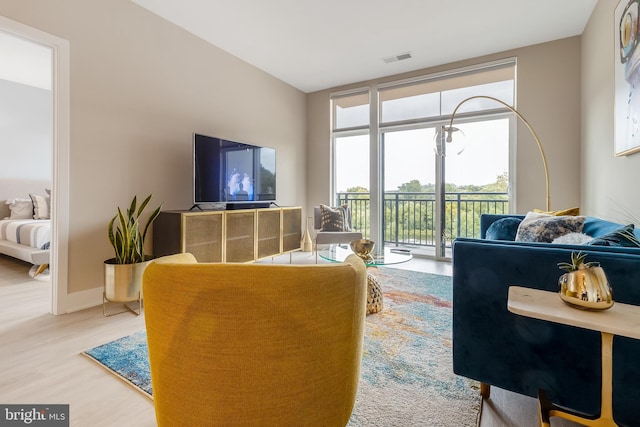 living room featuring visible vents, baseboards, wood finished floors, and floor to ceiling windows