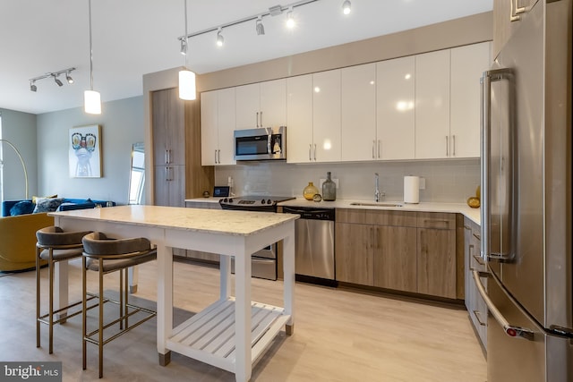 kitchen with backsplash, open floor plan, appliances with stainless steel finishes, hanging light fixtures, and a sink