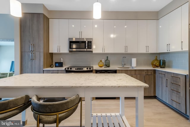 kitchen featuring a sink, appliances with stainless steel finishes, a breakfast bar area, and white cabinetry