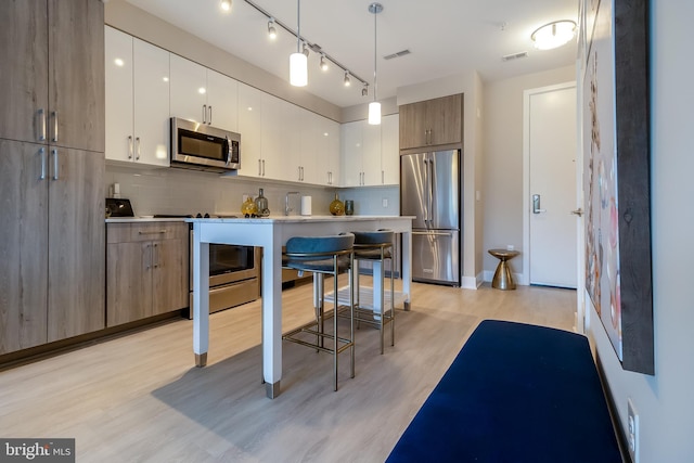 kitchen featuring visible vents, light wood-type flooring, stainless steel appliances, modern cabinets, and tasteful backsplash