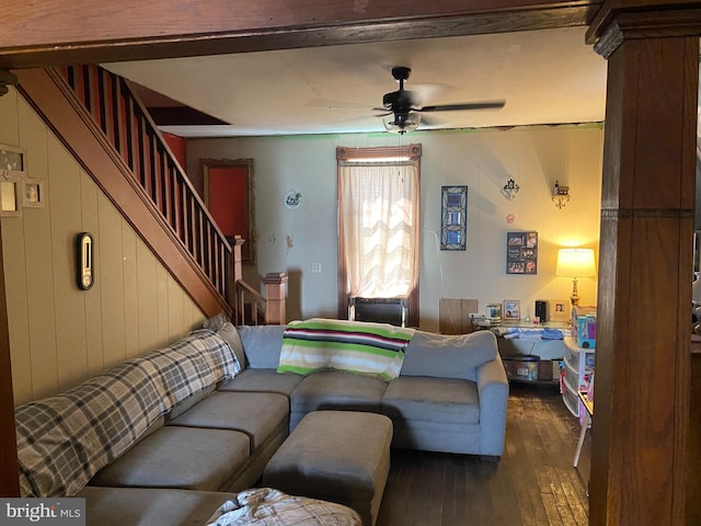 living room featuring ceiling fan, dark wood-type flooring, and wooden walls