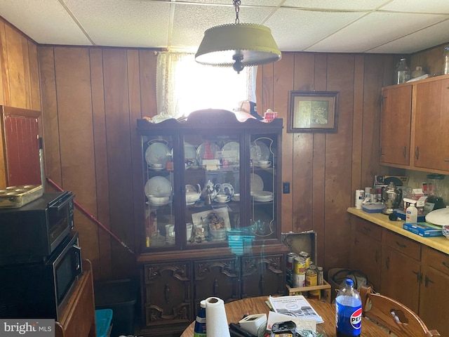 dining area featuring a paneled ceiling and wooden walls