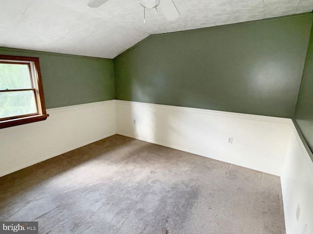 carpeted spare room featuring ceiling fan and vaulted ceiling