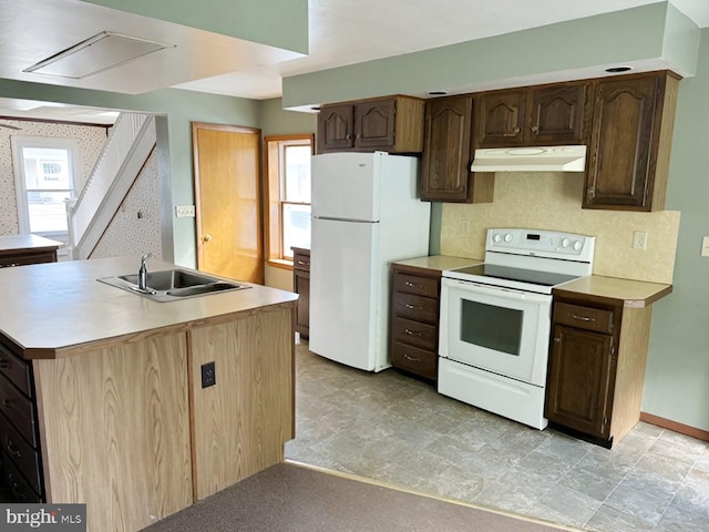 kitchen with white appliances, backsplash, a kitchen island with sink, sink, and dark brown cabinetry