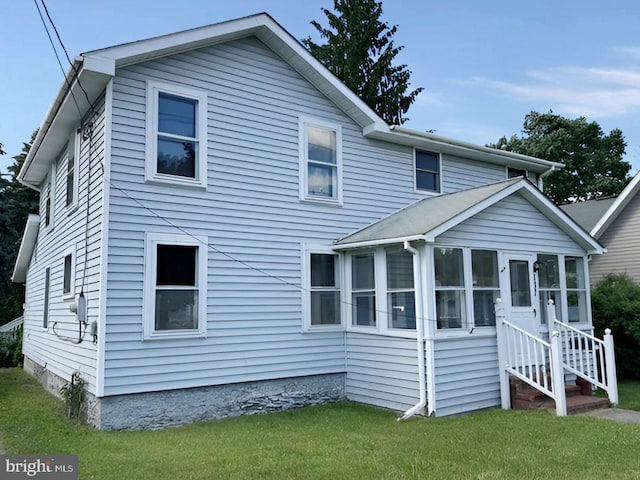 rear view of property featuring a lawn and a sunroom