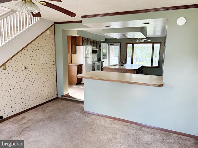 kitchen with white fridge, range with electric stovetop, light colored carpet, and crown molding