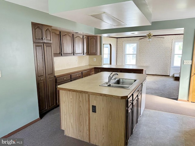 kitchen with dark colored carpet, sink, ceiling fan, an island with sink, and kitchen peninsula