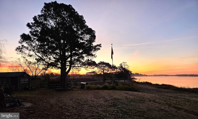 yard at dusk featuring a water view