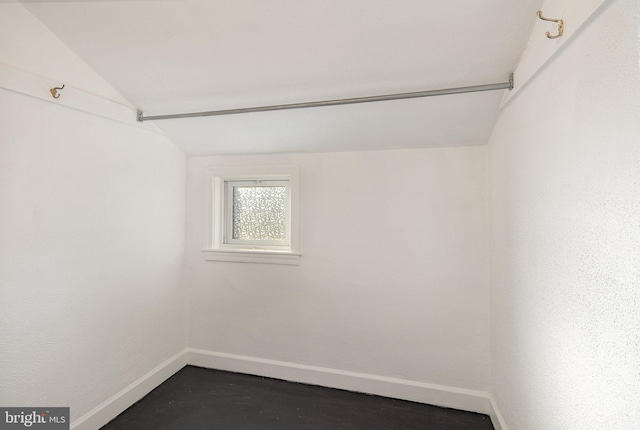 spare room featuring vaulted ceiling and concrete floors