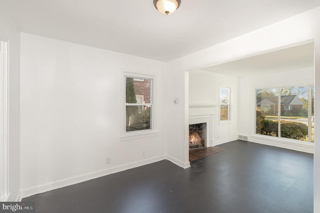 unfurnished living room with a brick fireplace and dark hardwood / wood-style floors