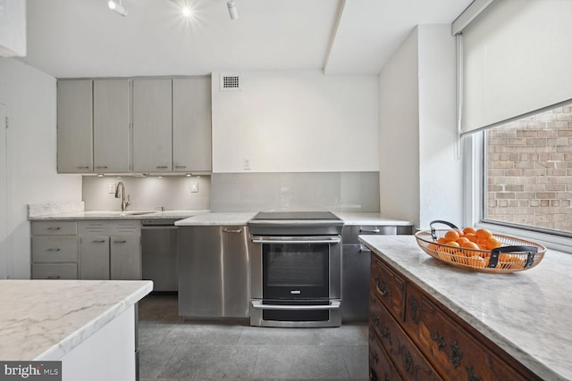 kitchen featuring tasteful backsplash, light stone countertops, appliances with stainless steel finishes, and sink