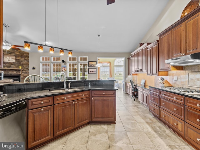 kitchen with a stone fireplace, hanging light fixtures, light tile patterned floors, stainless steel appliances, and sink