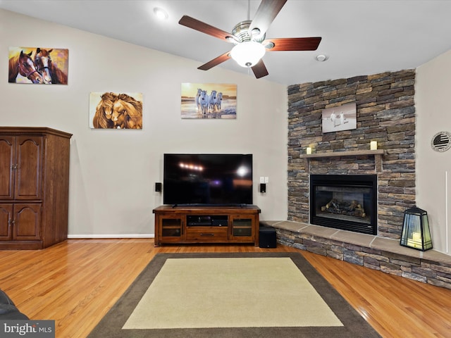 living room with hardwood / wood-style floors, a fireplace, vaulted ceiling, and ceiling fan