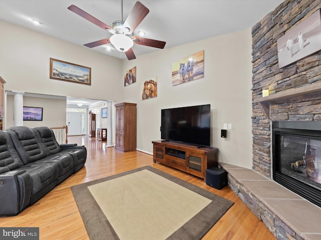 living room featuring ceiling fan, light wood-type flooring, and a fireplace