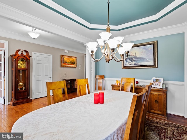 dining area featuring a chandelier, crown molding, wood-type flooring, and a raised ceiling