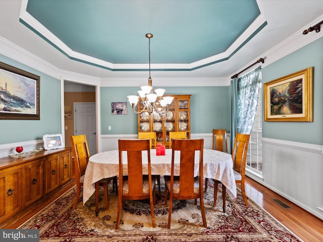 dining room featuring a notable chandelier, a raised ceiling, and ornamental molding