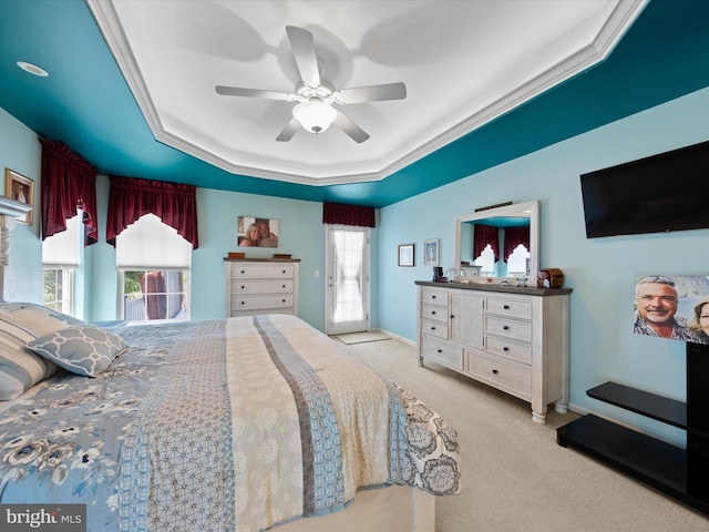 bedroom with ceiling fan, light carpet, and a tray ceiling