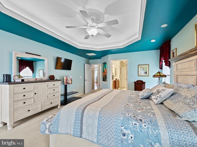 carpeted bedroom with ceiling fan, a raised ceiling, and ensuite bathroom