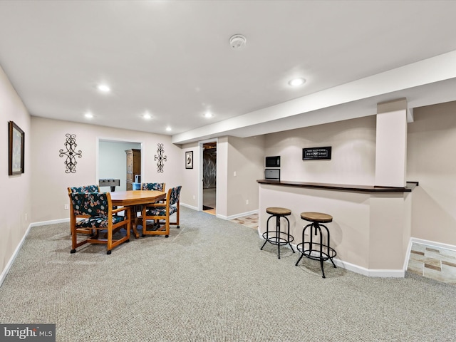 dining space with bar area and light colored carpet