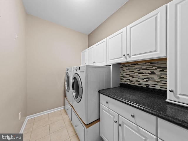 washroom with washing machine and clothes dryer, light tile patterned floors, and cabinets