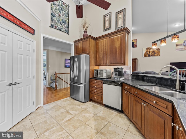 kitchen featuring dark stone countertops, light tile patterned floors, appliances with stainless steel finishes, ceiling fan, and sink