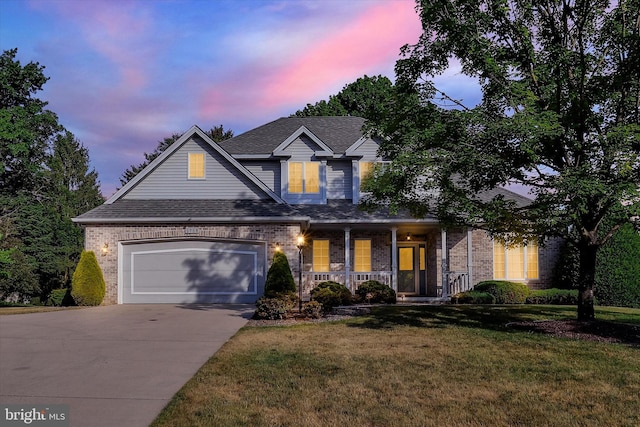 view of front of house featuring covered porch, a yard, and a garage