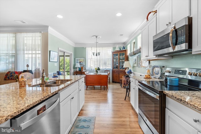 kitchen with white cabinetry, sink, light stone counters, crown molding, and appliances with stainless steel finishes