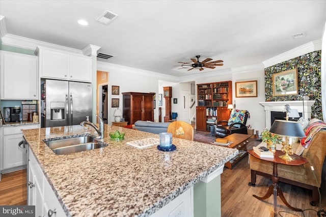 kitchen featuring sink, light stone counters, stainless steel refrigerator with ice dispenser, white cabinets, and ornamental molding