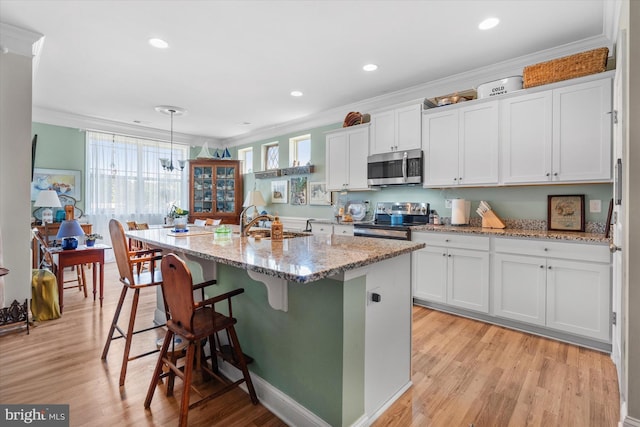 kitchen featuring crown molding, white cabinets, an island with sink, and appliances with stainless steel finishes