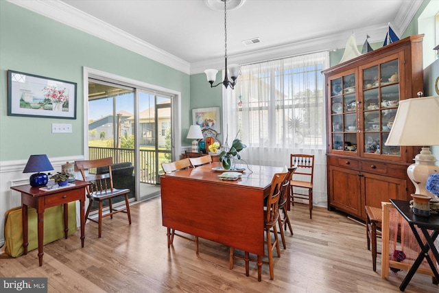 dining space featuring a notable chandelier, ornamental molding, and light hardwood / wood-style flooring