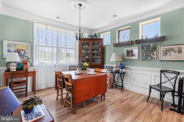 dining space featuring a chandelier, light wood-type flooring, and ornamental molding