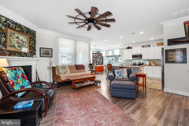 living room with hardwood / wood-style flooring, ceiling fan, and crown molding