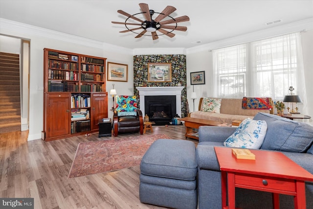 living room featuring ceiling fan, ornamental molding, and light hardwood / wood-style flooring