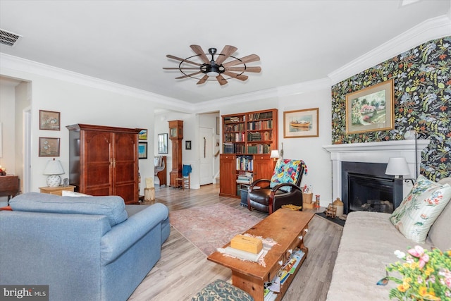 living room with ceiling fan, crown molding, and light hardwood / wood-style flooring