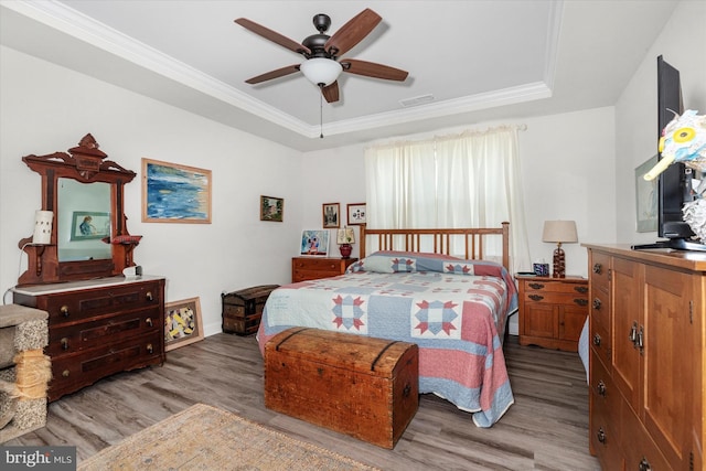 bedroom with ceiling fan, light hardwood / wood-style floors, ornamental molding, and a tray ceiling