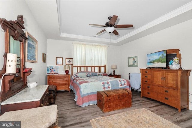 bedroom featuring a raised ceiling, ceiling fan, dark hardwood / wood-style floors, and ornamental molding