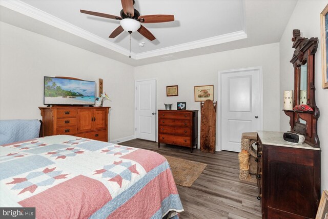 bedroom with ceiling fan, wood-type flooring, ornamental molding, and a tray ceiling