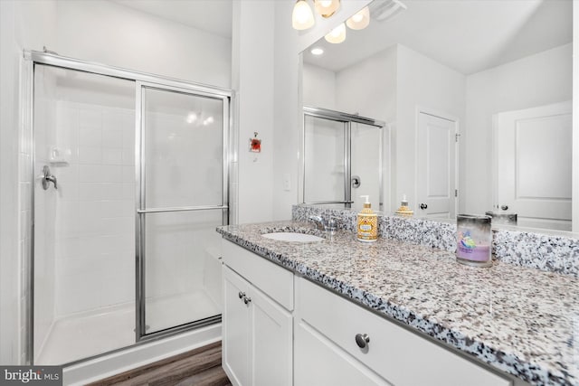 bathroom featuring hardwood / wood-style flooring, vanity, and an enclosed shower