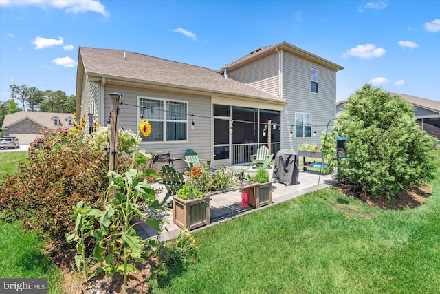 rear view of house featuring a lawn, a sunroom, and a patio