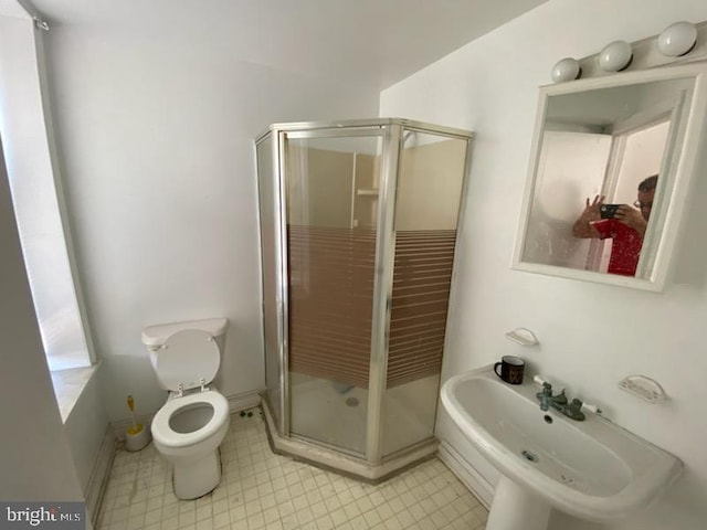 bathroom with toilet, a shower with door, and sink