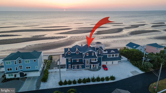 aerial view at dusk featuring a water view