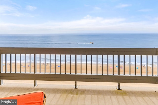 balcony with a water view and a view of the beach