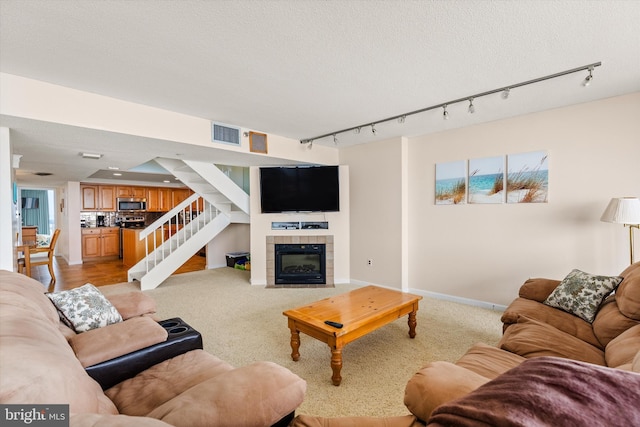 living room with a textured ceiling, rail lighting, and a tile fireplace