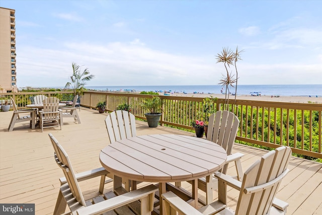 wooden terrace featuring a water view and a beach view